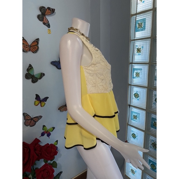 เสื้อแขนกุดผ้าชีฟองสีเหลืองด้านหน้าครอบด้วยผ้าซีทูปักดอกไม้สีขาวไม้ชายระบายสองชั้นตัดด้วยขอบสีดำ