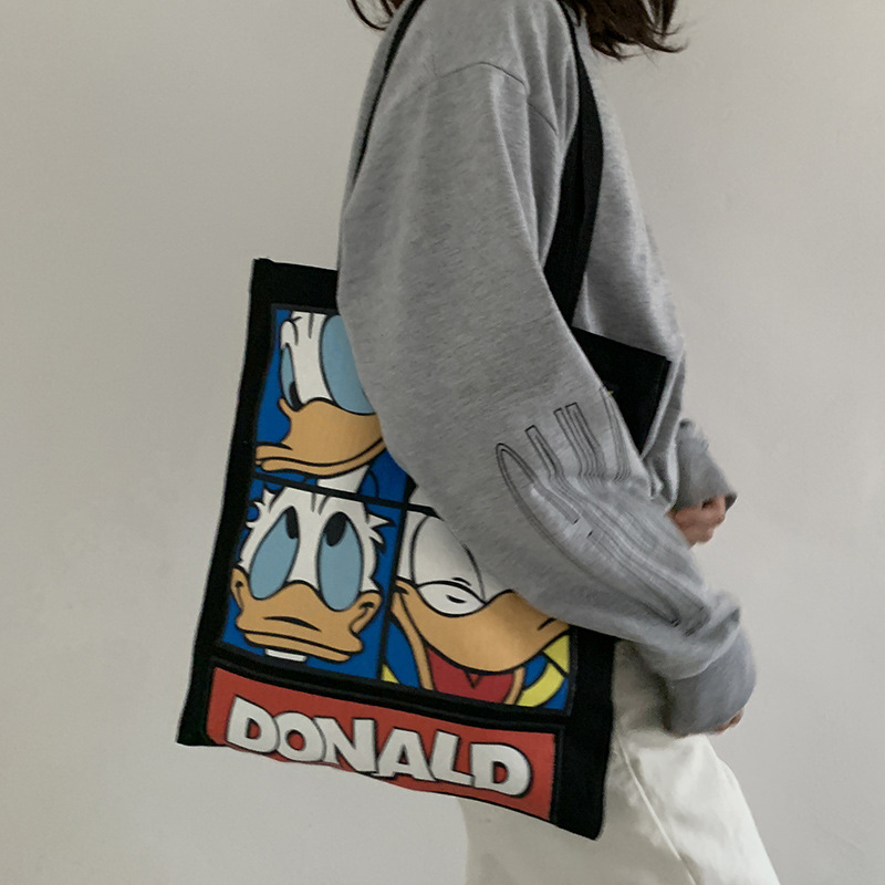 ภาพหน้าปกสินค้ากระเป๋าผ้าใบสะพายไหล่ลายการ์ตูน Donald Duck จากร้าน xiaofeifei.th บน Shopee