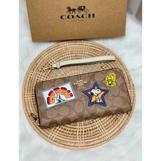 กระเป๋าเงินใบยาว COACH X PEANUTS LONG ZIP AROUND WALLET IN SIGNATURE CANVAS WITH VARSITY PATCHES