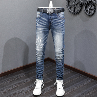 Amiri High Street แฟชั่นผู้ชายใหม่กางเกงยีนส์สีน้ำเงินผอมพิมพ์โลโก้แพทช์ที่มีคุณภาพสูง Hip Hop ปุ่มกางเกงยีนส์ผู้ชาย